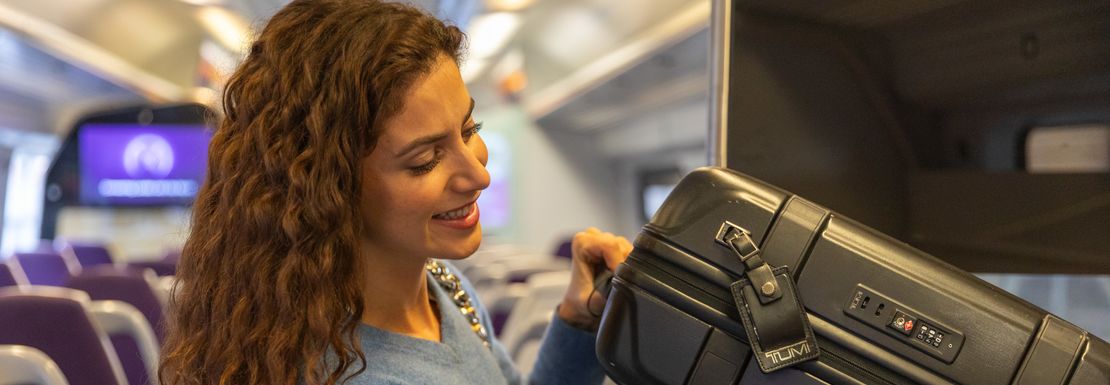 A woman easily stows away her baggage on board a Heathrow Express train
